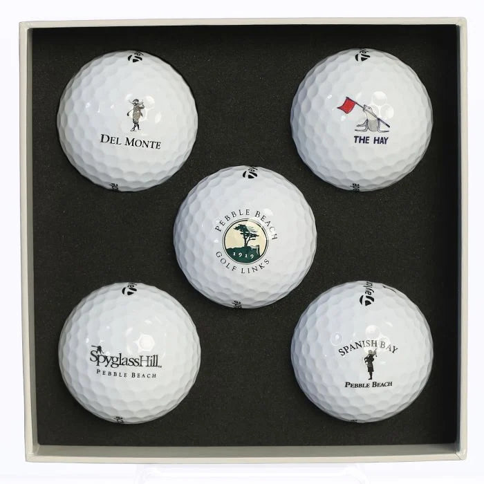 Five golf balls Delmonte golf, Pebble beach golf links, The Hay golf, Spanish bay golf links, and spyglass hill golf course logos in a black display box