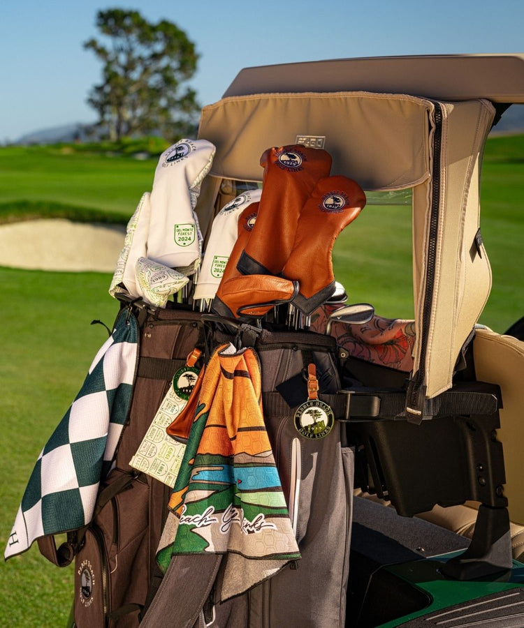 Golf cart with golf bags featuring golf towels, bag tags, zipper pouches, and golf club headcovers. 
