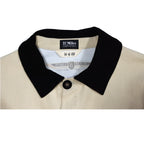 Close-up of a beige jacket with a black collar and visible pebble beach concours labels with white background