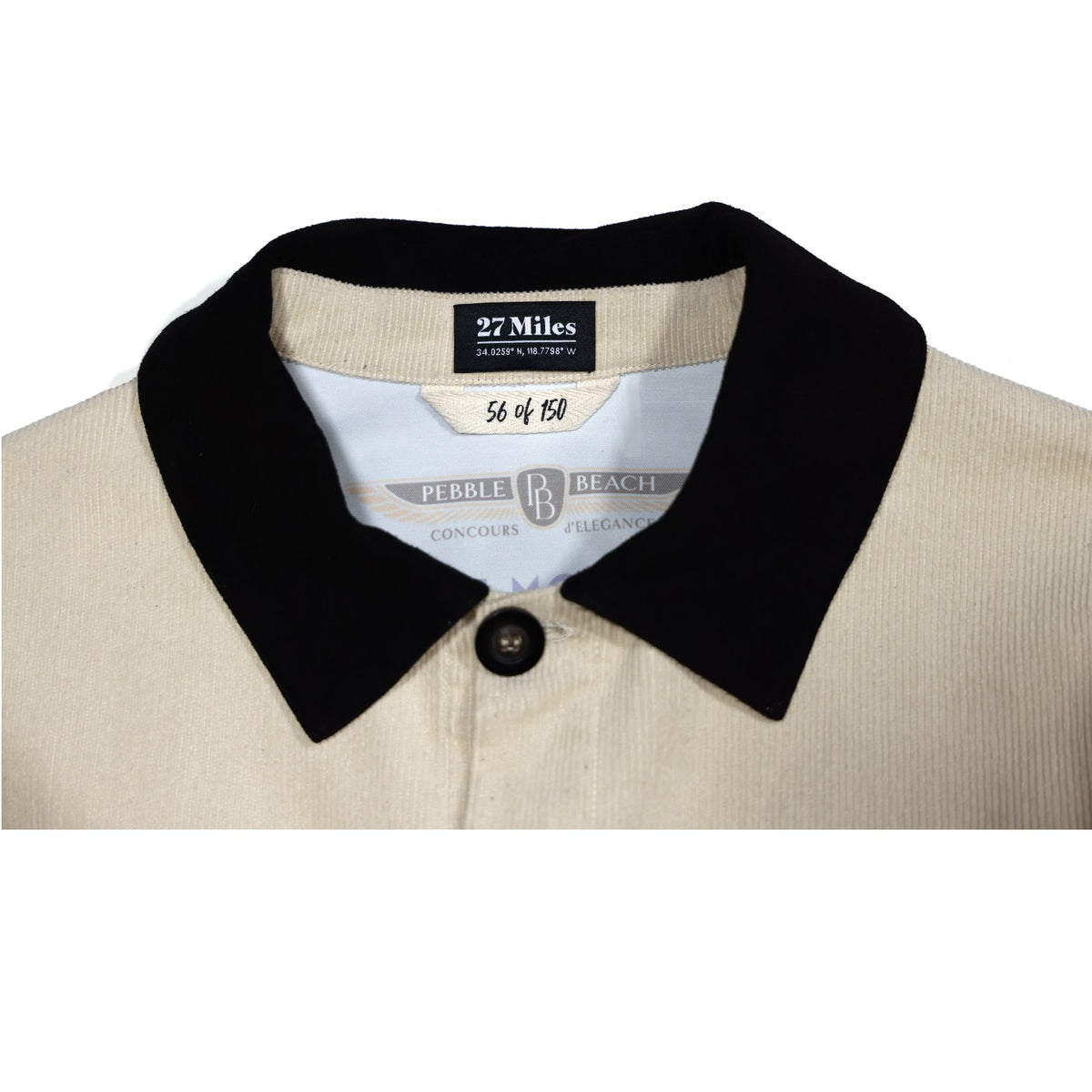 Close-up of a beige jacket with a black collar and visible pebble beach concours labels with white background