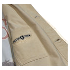 Beige jacket with a visible pebble beach concours logo on a white background