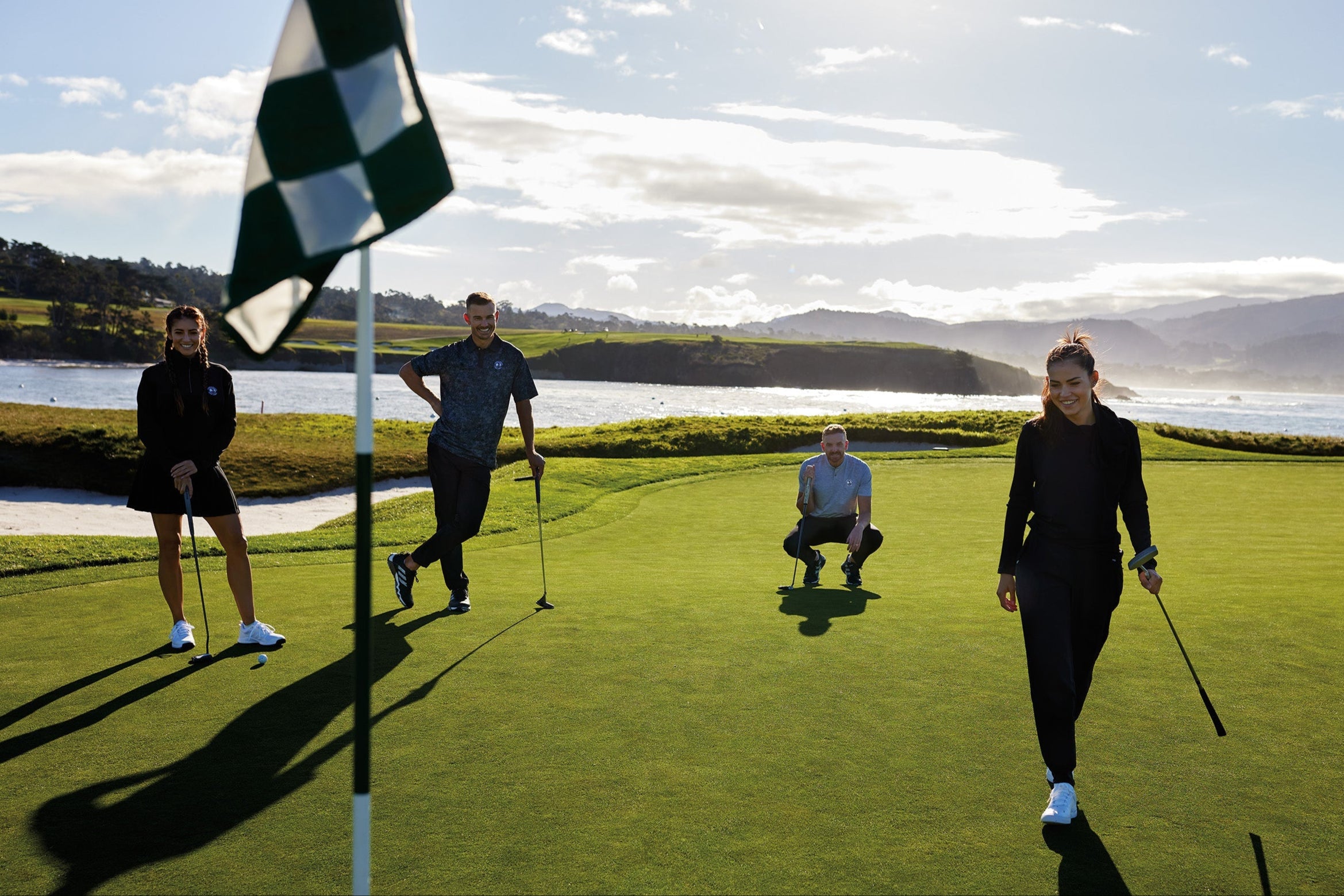 Four people on a golf course with a scenic background