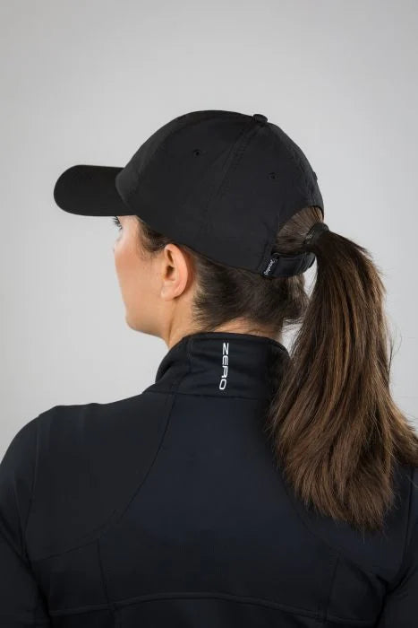Person wearing a black cap and black jacket with a brand logo on a gray background
