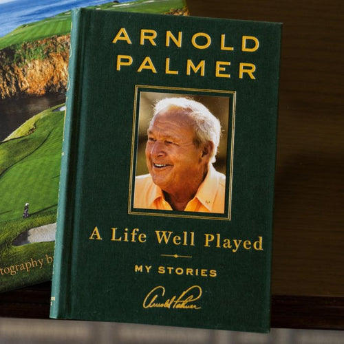 Book titled 'A Life Well Played' by Arnold Palmer with a golf course image in the background.