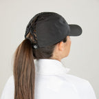 Person wearing a black cap with a ponytail, against a plain white background