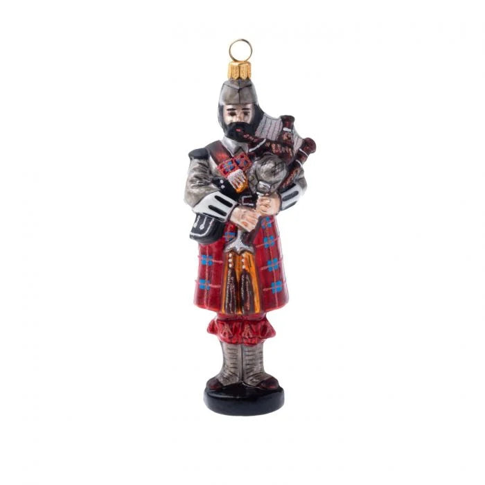 Glass ornament of a male Scottish bagpiper in tartan kilt on a white background