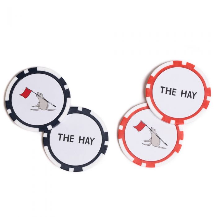 Two poker chips with one red and white other blue and white with 'The Hay' branding on one side and Cynthia the sea lion on the other on a white background