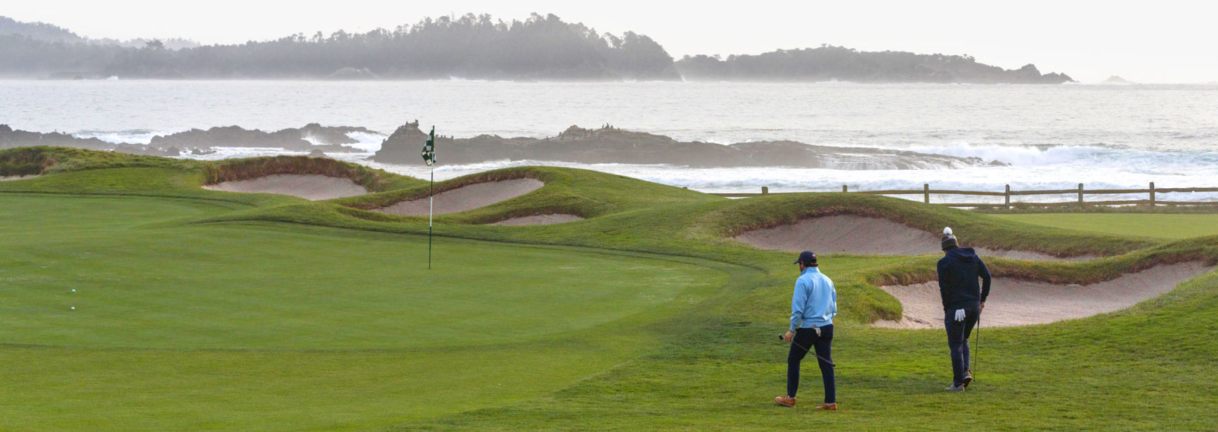 Two golfers on Pebble Beach golf course with ocean view