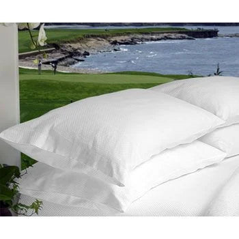 White pillows on a bed with a scenic view of a golf course and water in the background